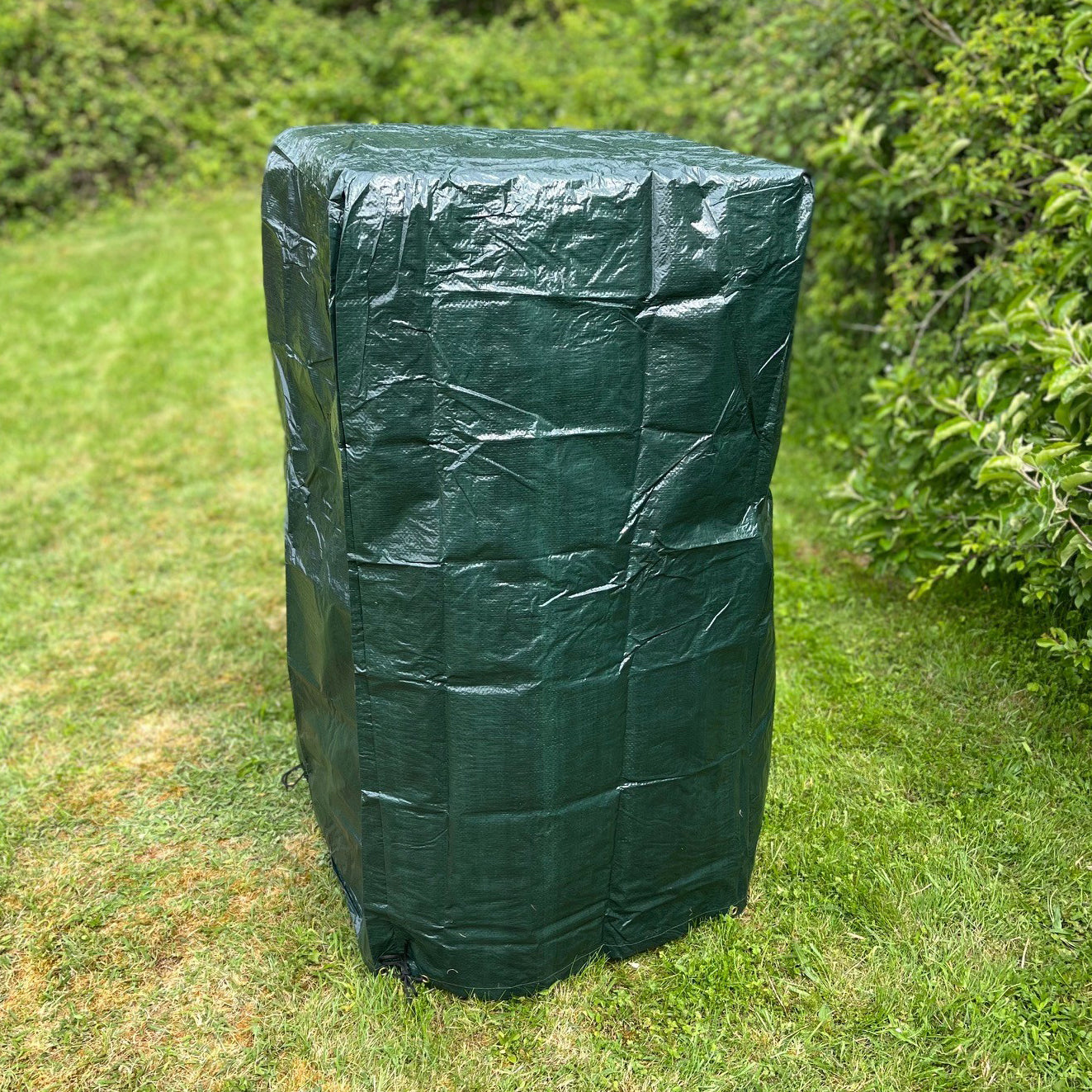 A green waterproof stacking chair cover placed on a chair outdoors, presumably to protect it from the elements.