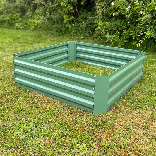A green painted steel raised vegetable bed placed on grass.