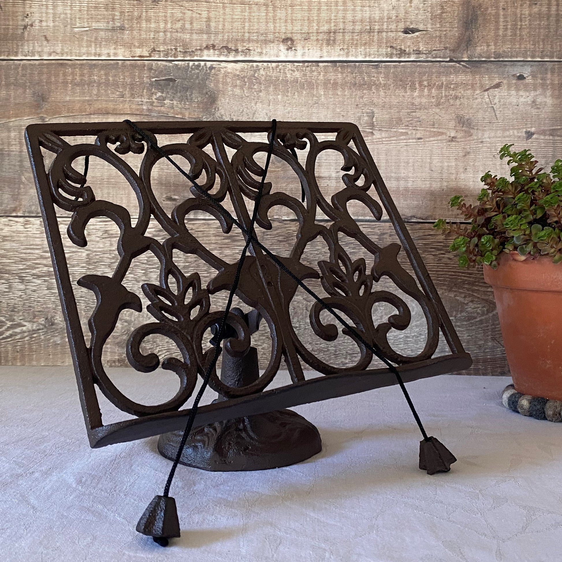 A traditional cast iron ornate cookbook stand with a floral pattern, displayed in a kitchen setting.