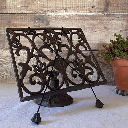 A traditional cast iron ornate cookbook stand with a floral pattern, displayed in a kitchen setting.