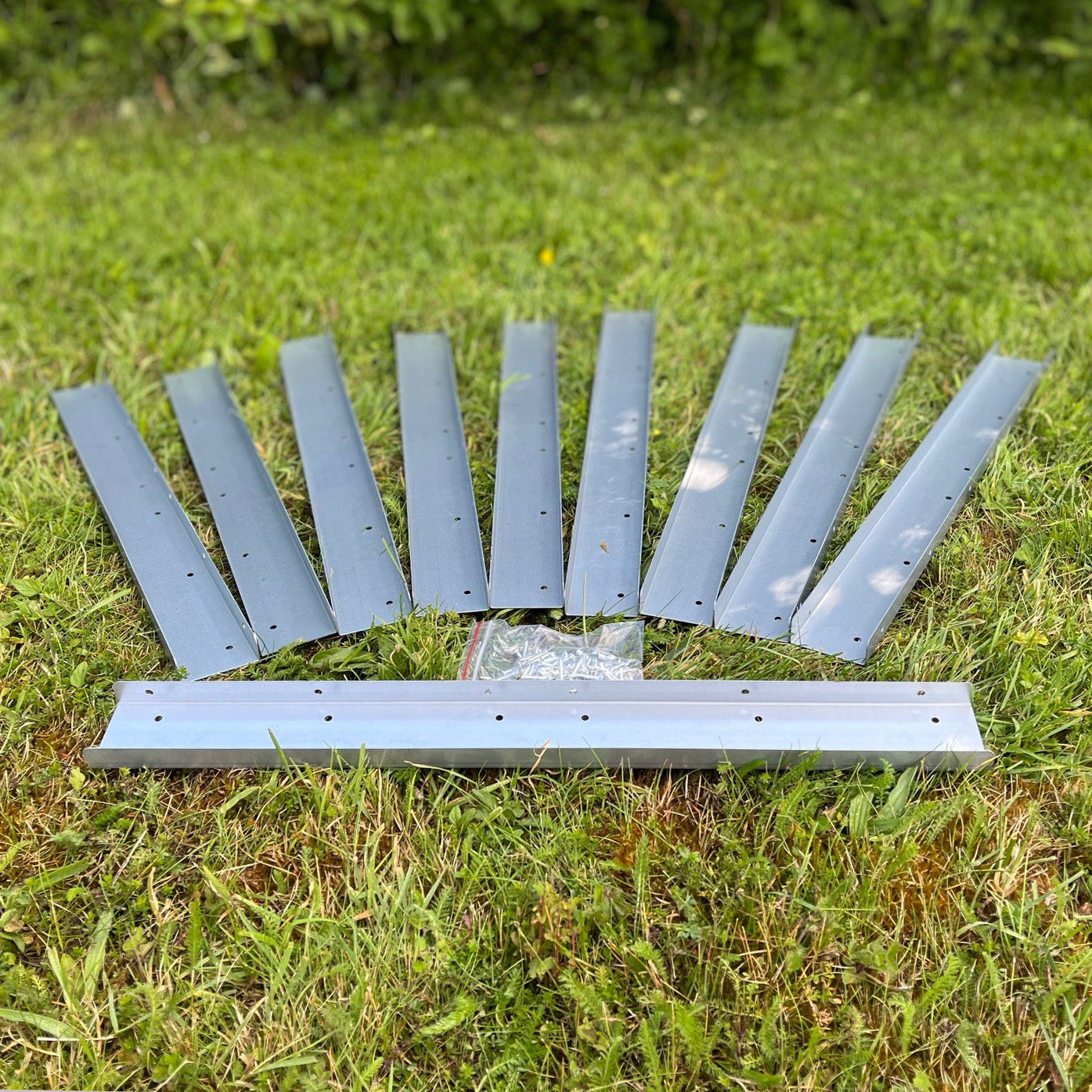 A set of silver galvanised steel trellis extension brackets laid out on grass.