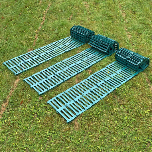 A green plastic garden track path laid out on grass, consisting of multiple connected panels.