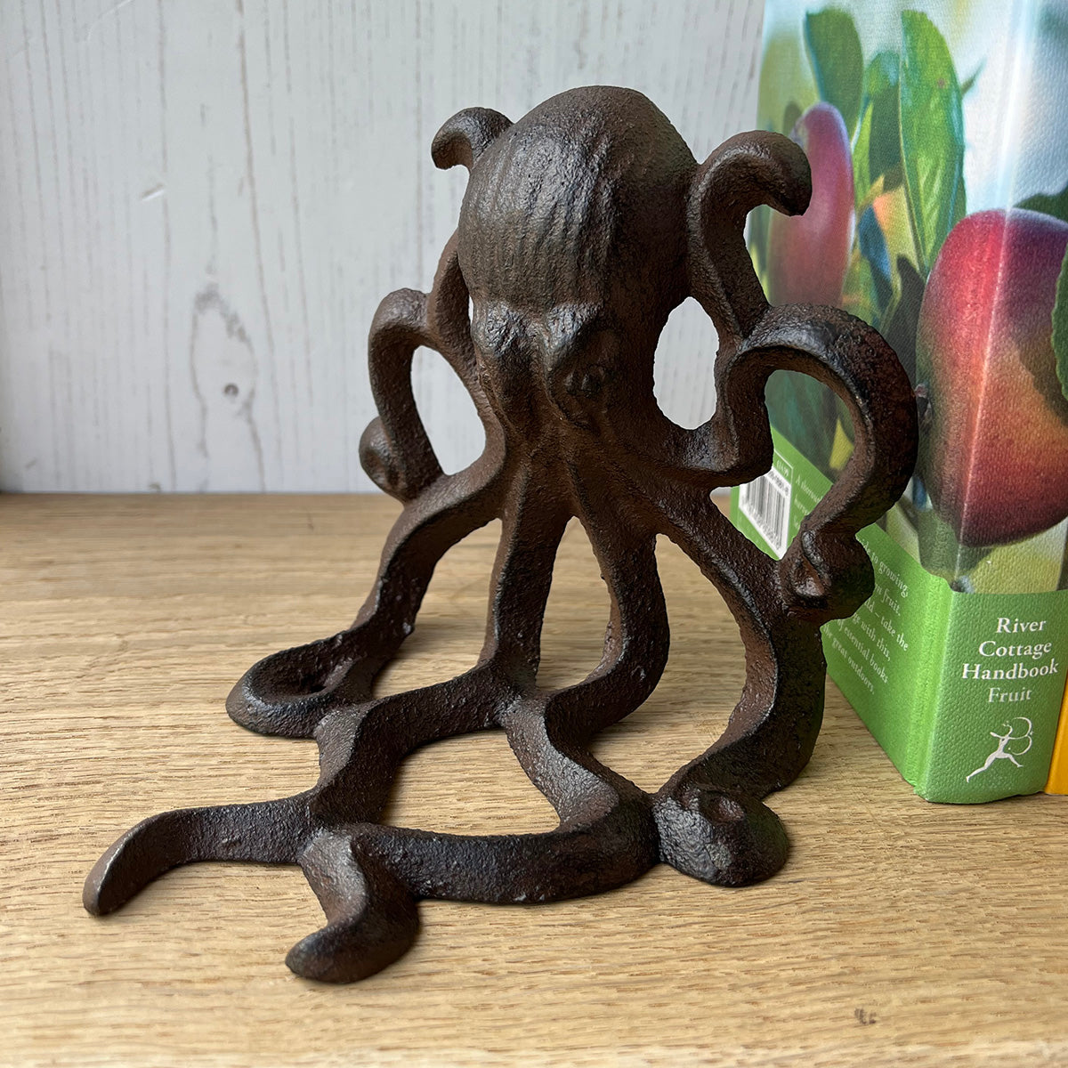 A pair of cast iron bookends shaped like octopuses, with a vintage brown finish, displayed on a wooden surface.
