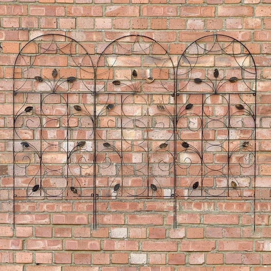 A set of three leaf design metal trellises placed against a brick wall, with a bronze coating and intricate leaf patterns.