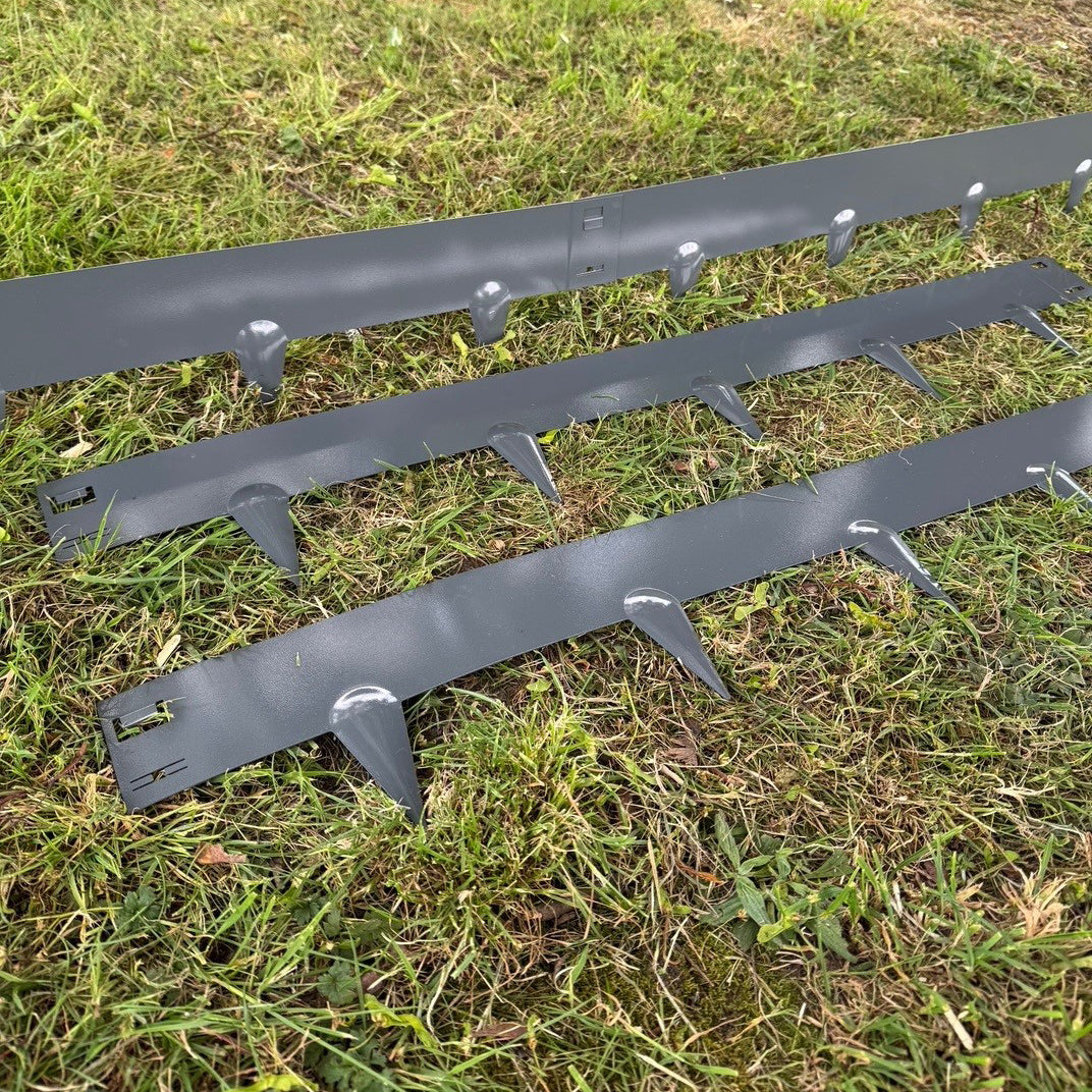 Five grey metal garden lawn and border edging panels laid out on grass, showing interlocking design and spiked feet.