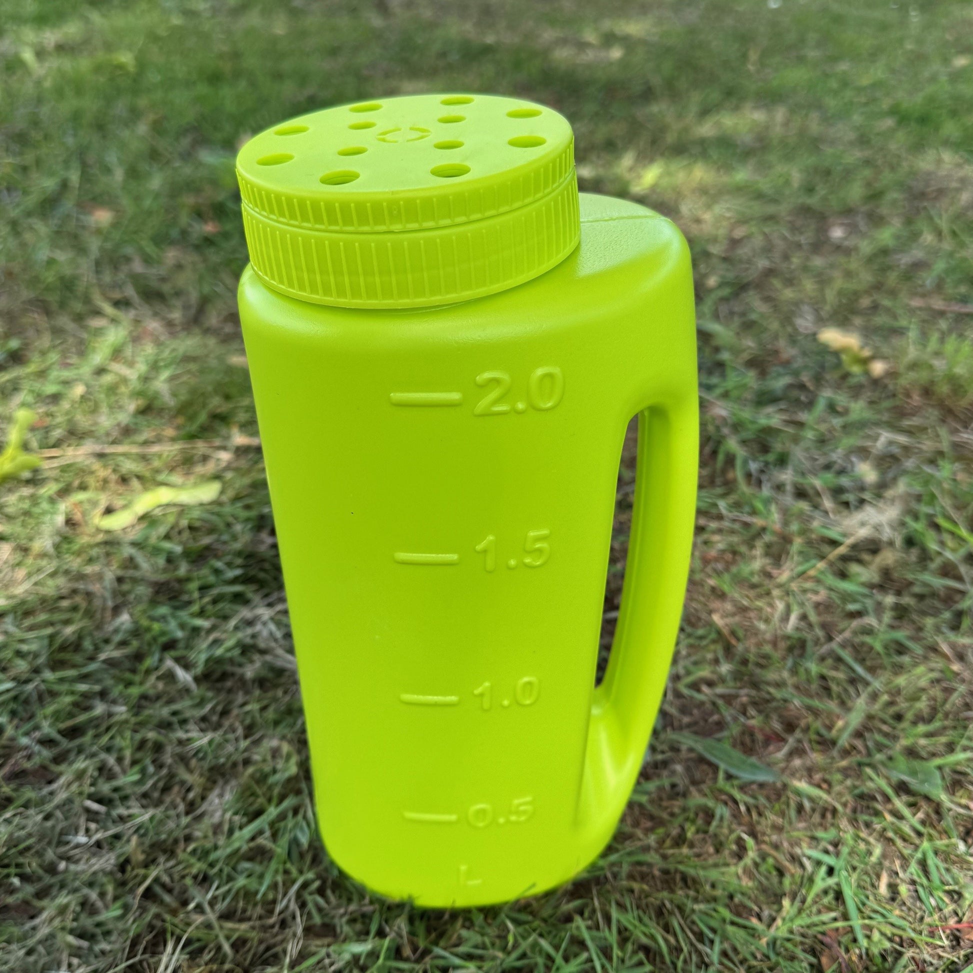 Green plastic bottle with measurement markings on a grassy background
