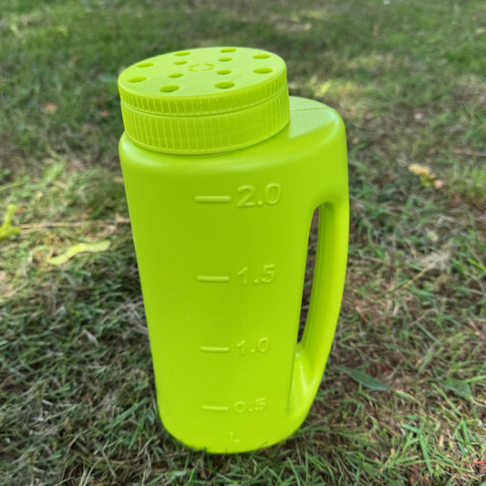 Green plastic bottle with measurement markings on a grassy background