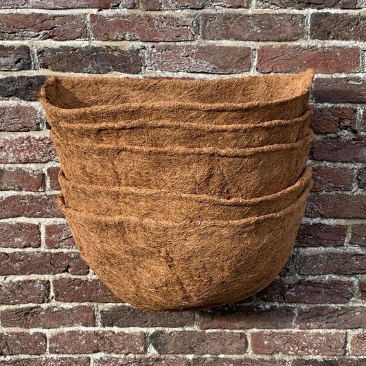 A stack of brown coco wall basket planter liners against a brick wall.