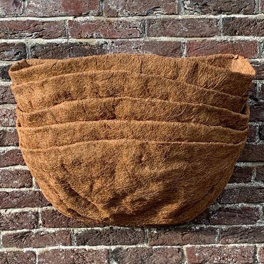 A brown coco wall basket planter liner displayed against a brick wall.