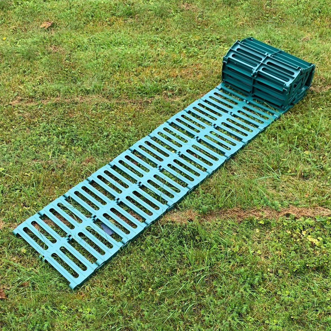 A green plastic garden track path laid out on grass, consisting of multiple connected panels.