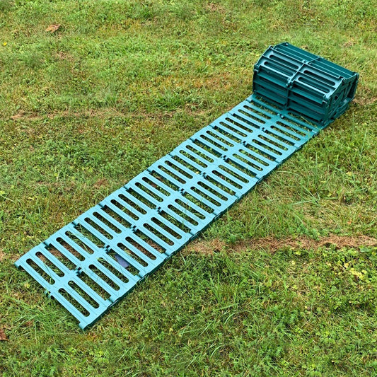 A green plastic garden track path laid out on grass, consisting of multiple connected panels.