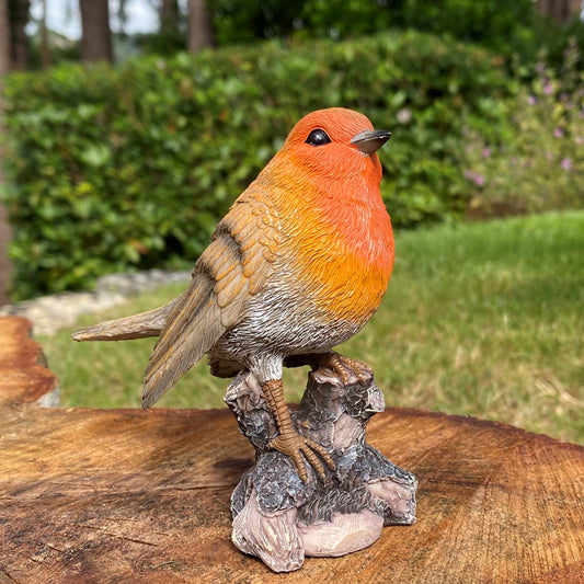 A hand painted resin garden ornament of a robin perched on a tree stump.
