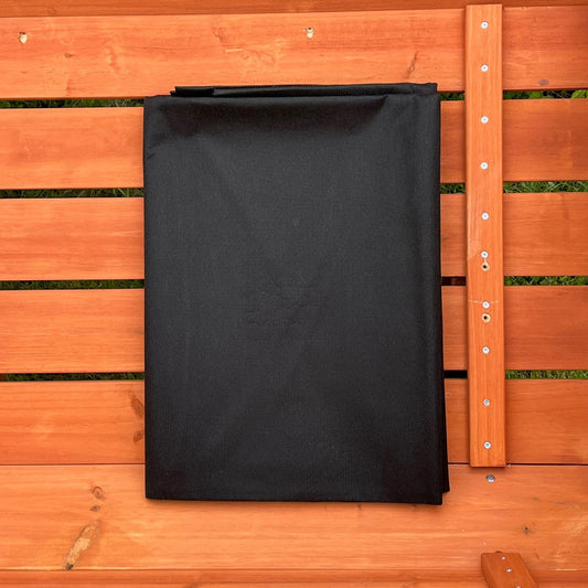 A black landscape fabric liner placed on a wooden surface, presumably the product referred to as the 'Liner for Large Veg Trough Planter'.