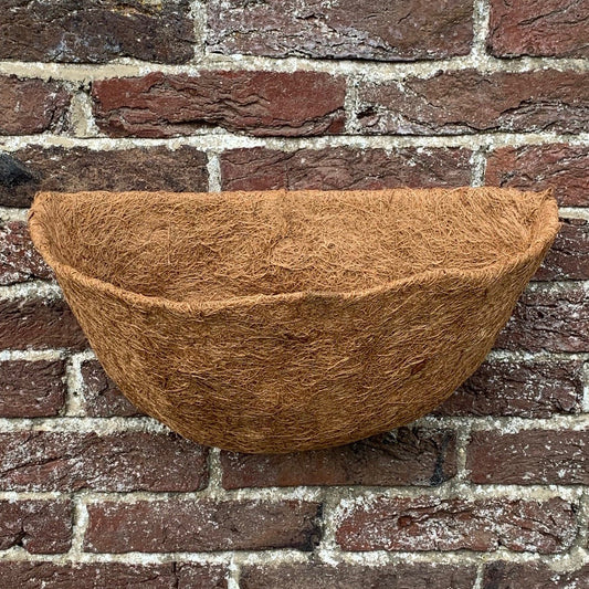 A brown coco wall basket planter liner placed against a brick wall.
