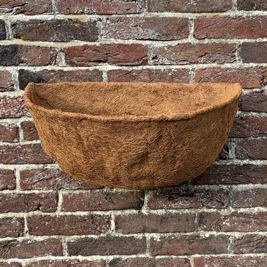 A brown coco wall basket planter liner shaped to fit into a basket, displayed against a brick wall background.