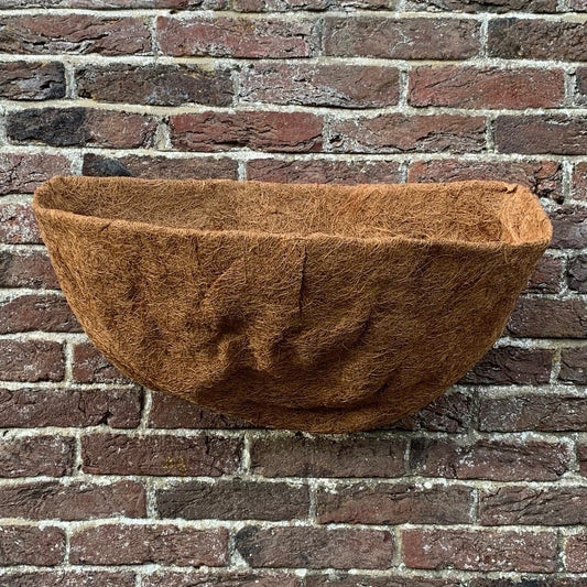 A brown coco wall basket planter liner displayed against a brick wall background.