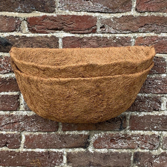 A brown coco wall basket planter liner displayed against a brick wall background.