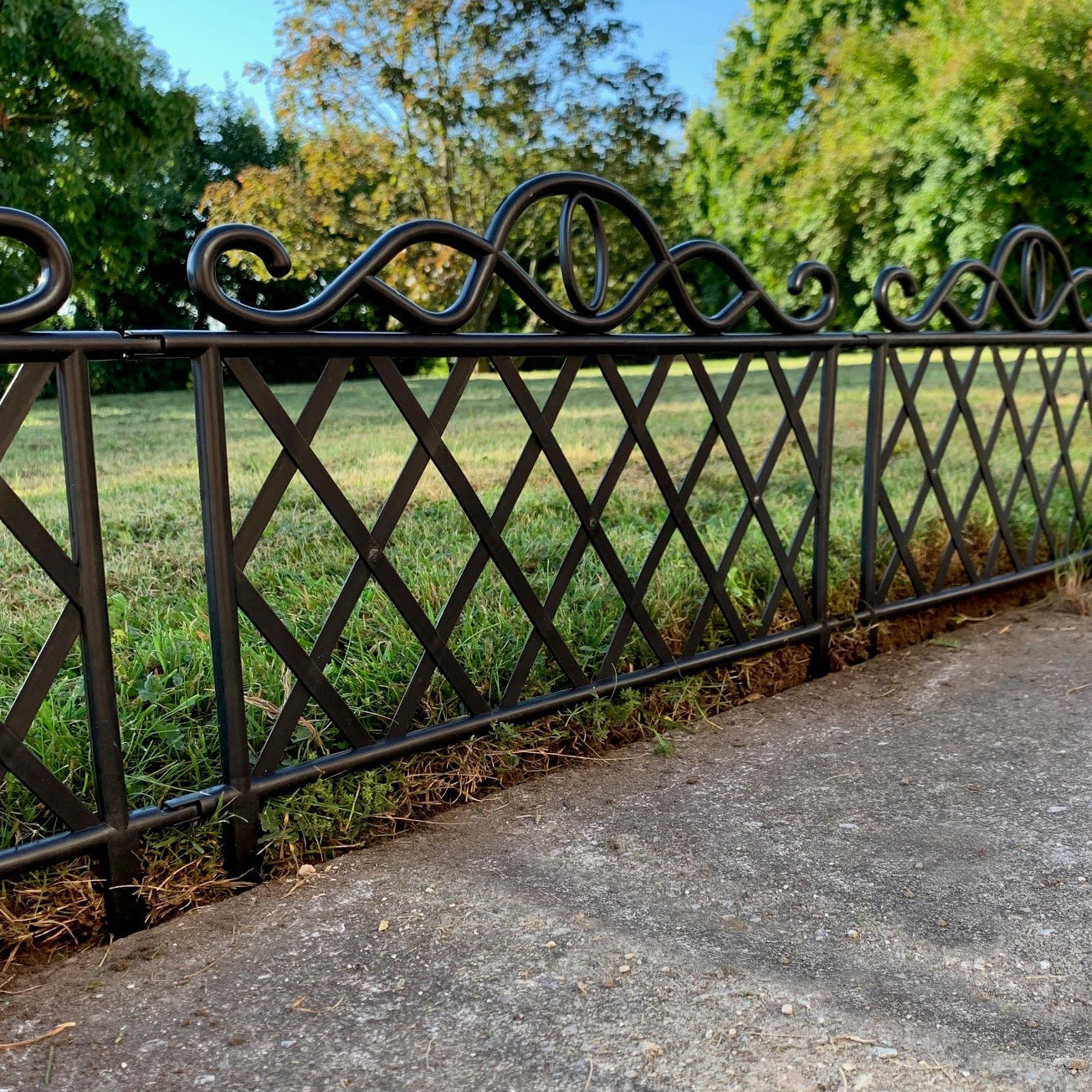 A set of black plastic ornamental lawn edging panels arranged along a pathway, featuring a traditional geometric design.