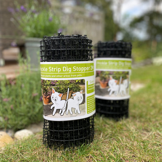 Two rolls of black plastic prickly strips designed to deter animals from flowerbeds, displayed on grass.