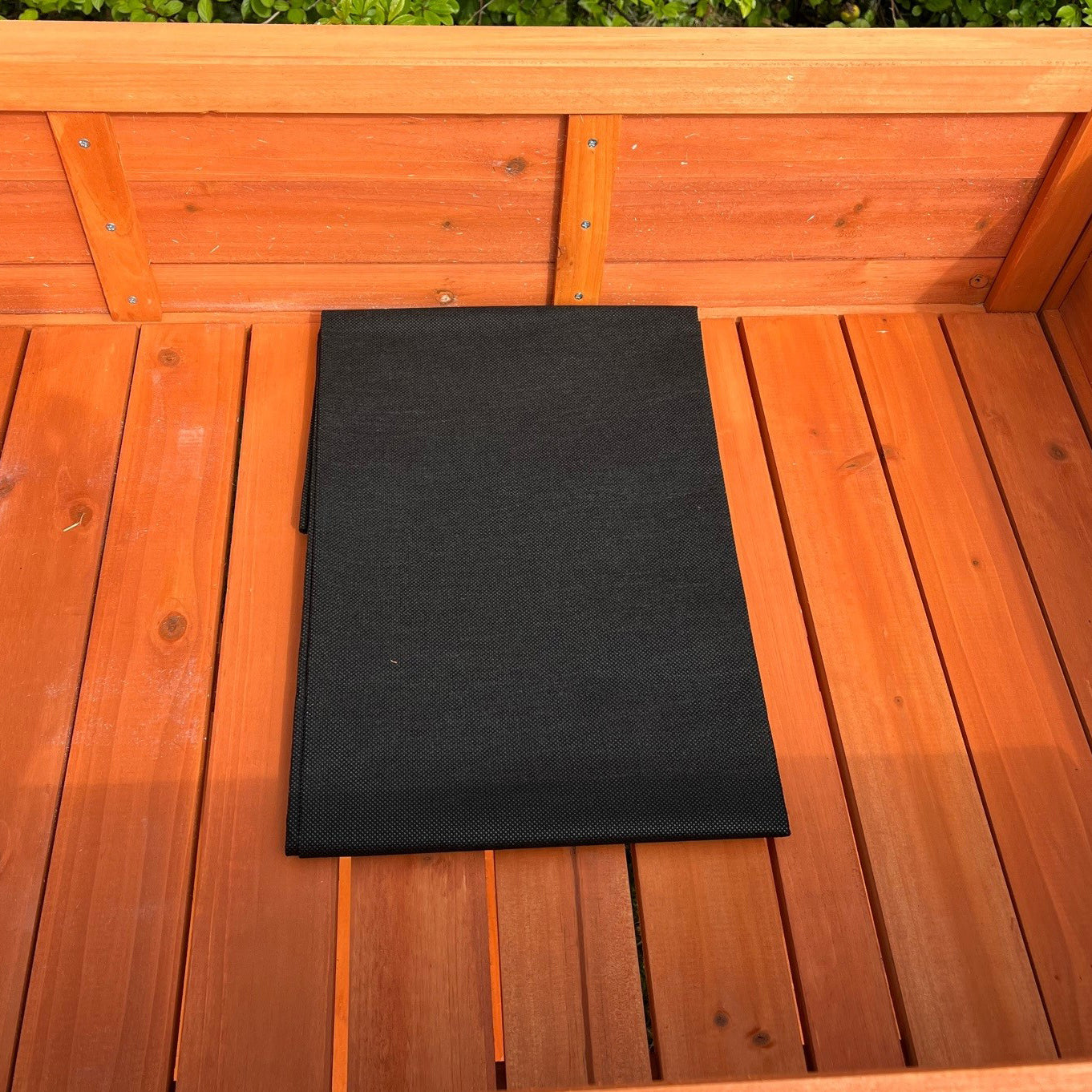 A black liner placed inside a wooden raised herb planter.