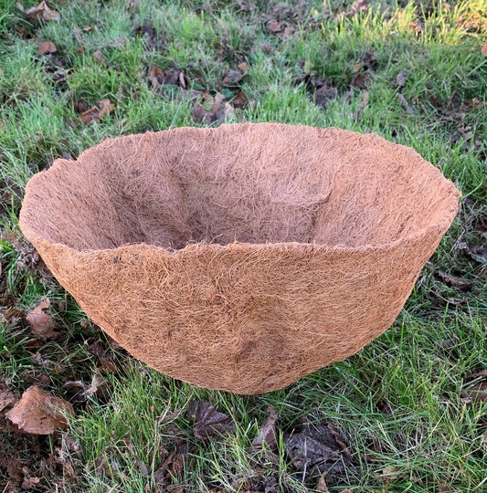 A brown coco hanging basket planter liner placed on grass.