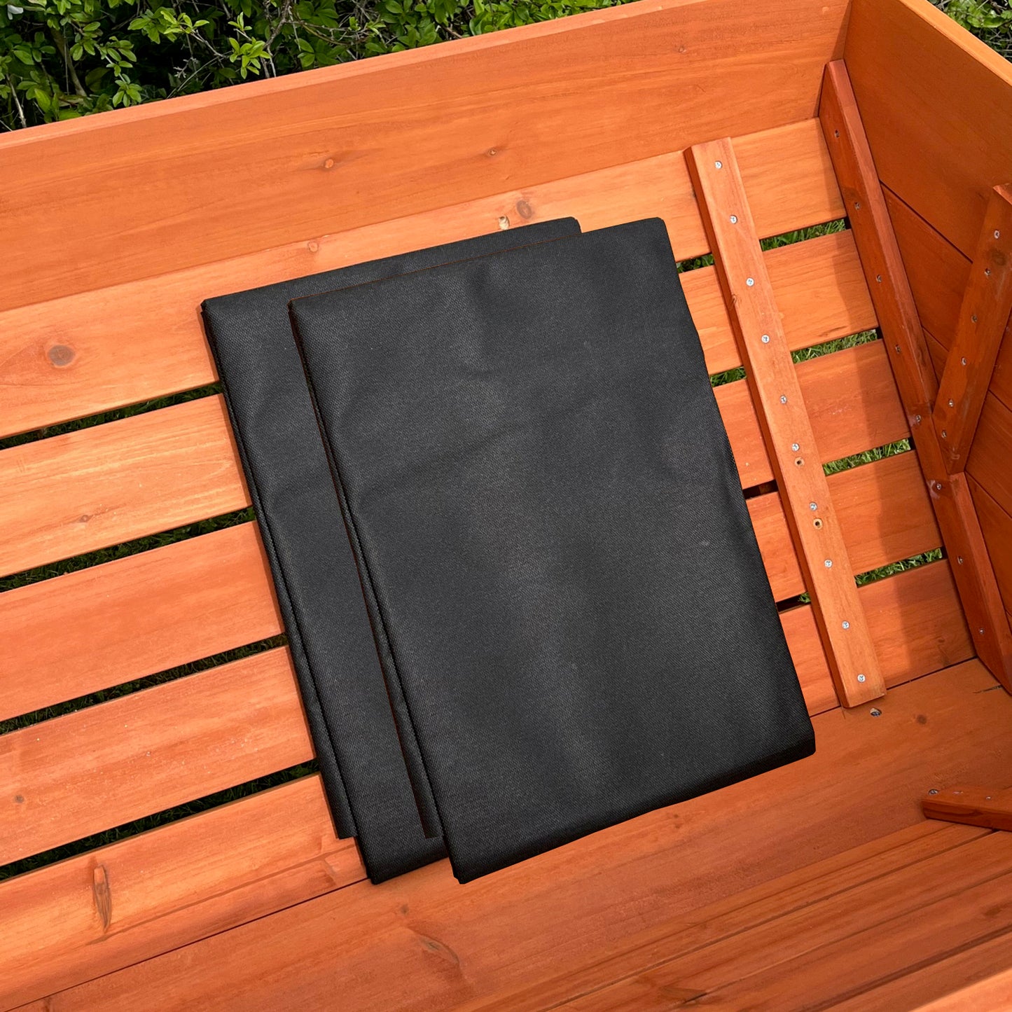 Two black landscape fabric liners placed inside a wooden raised bed planter.