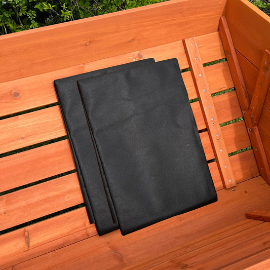 Two black landscape fabric liners placed inside a wooden raised bed planter.