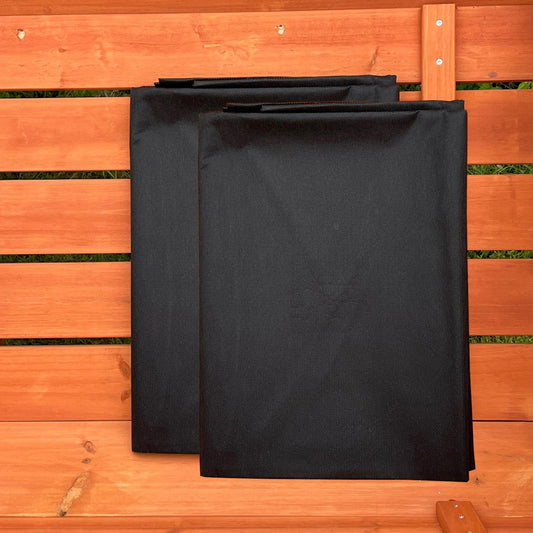 Two black landscape fabric liners placed on a wooden surface.