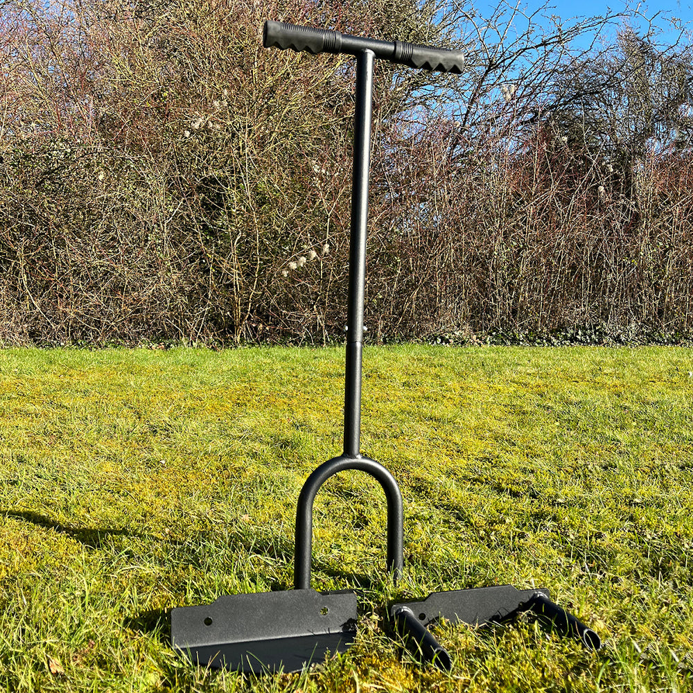 A black lawn aerator tool with a solid tine aerator head, lawn edger head, and hollow tine aerator head, displayed on a grassy surface.