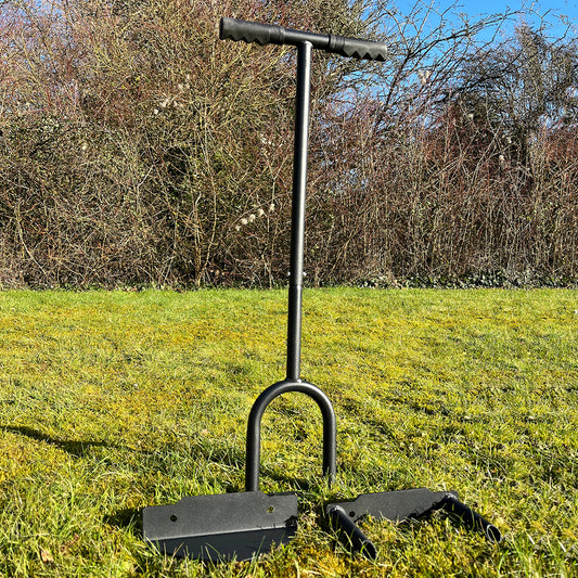 A black lawn aerator tool with a solid tine aerator head, lawn edger head, and hollow tine aerator head, displayed on a grassy surface.