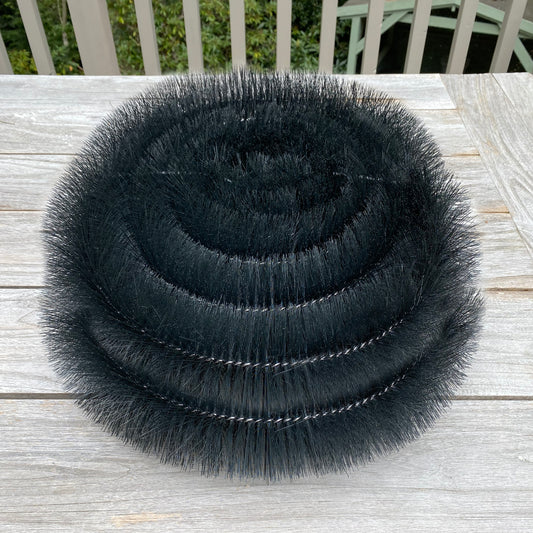 Stack of black bristle brushes on a wooden surface