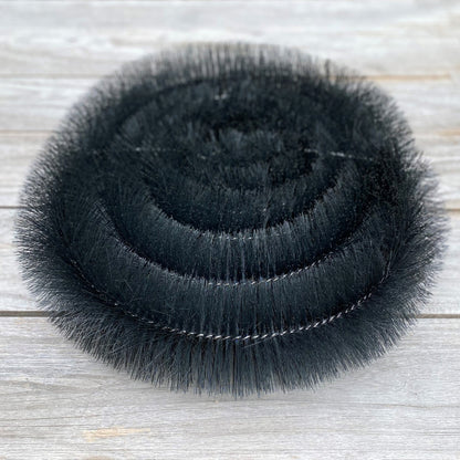 Stack of black gutter brush protection on a wooden surface