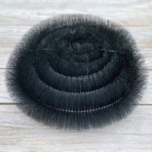 Stack of black gutter brush protection on a wooden surface