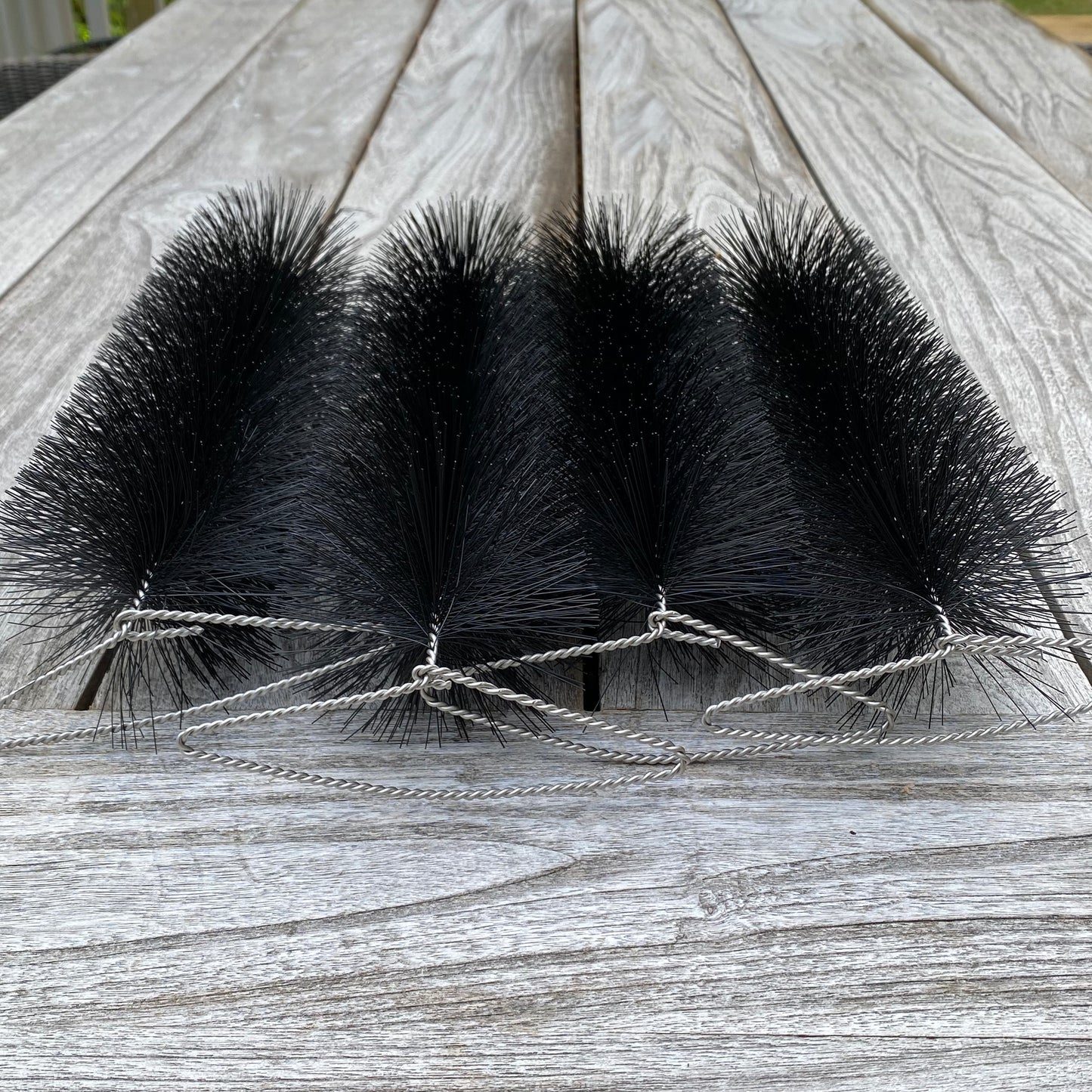 Four black bristle brushes tied together on a wooden surface