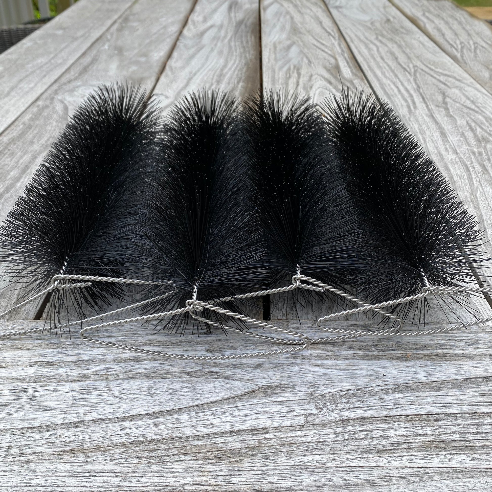Four black bristle brushes tied together on a wooden surface