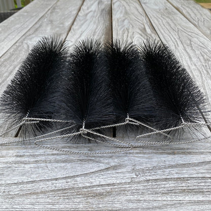 Four black bristle brushes tied together on a wooden surface