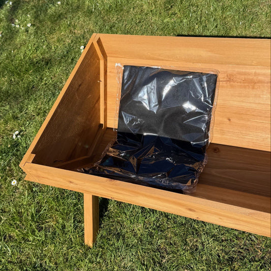 Wooden planter with a black liner inside on grass