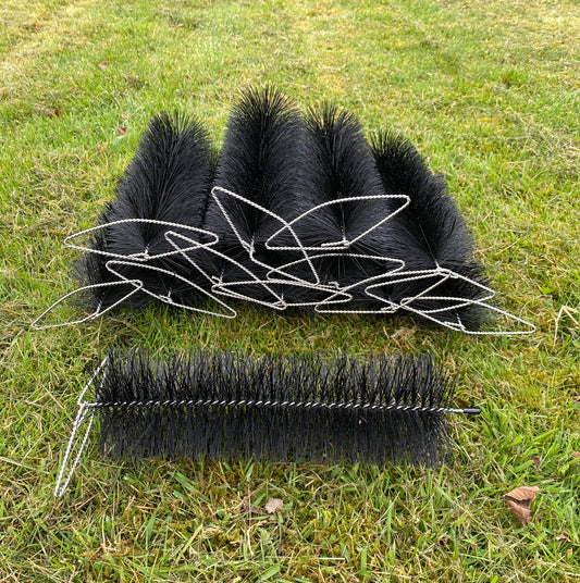 Three black wire and brush gutter downpipe plugs on grass