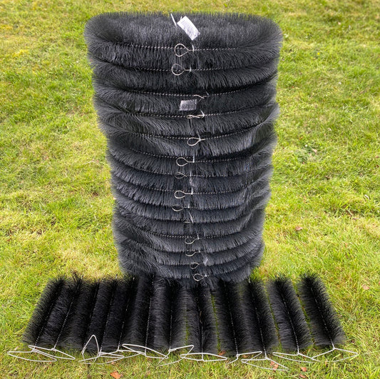 Stack of black plastic pipes with hooks on a grassy background